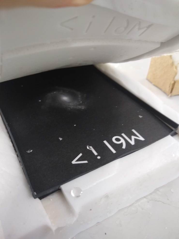 The silicone mould for M61 being held open. Inside the mould is the black and white galaxy image and a plastic frame holding the image in place.